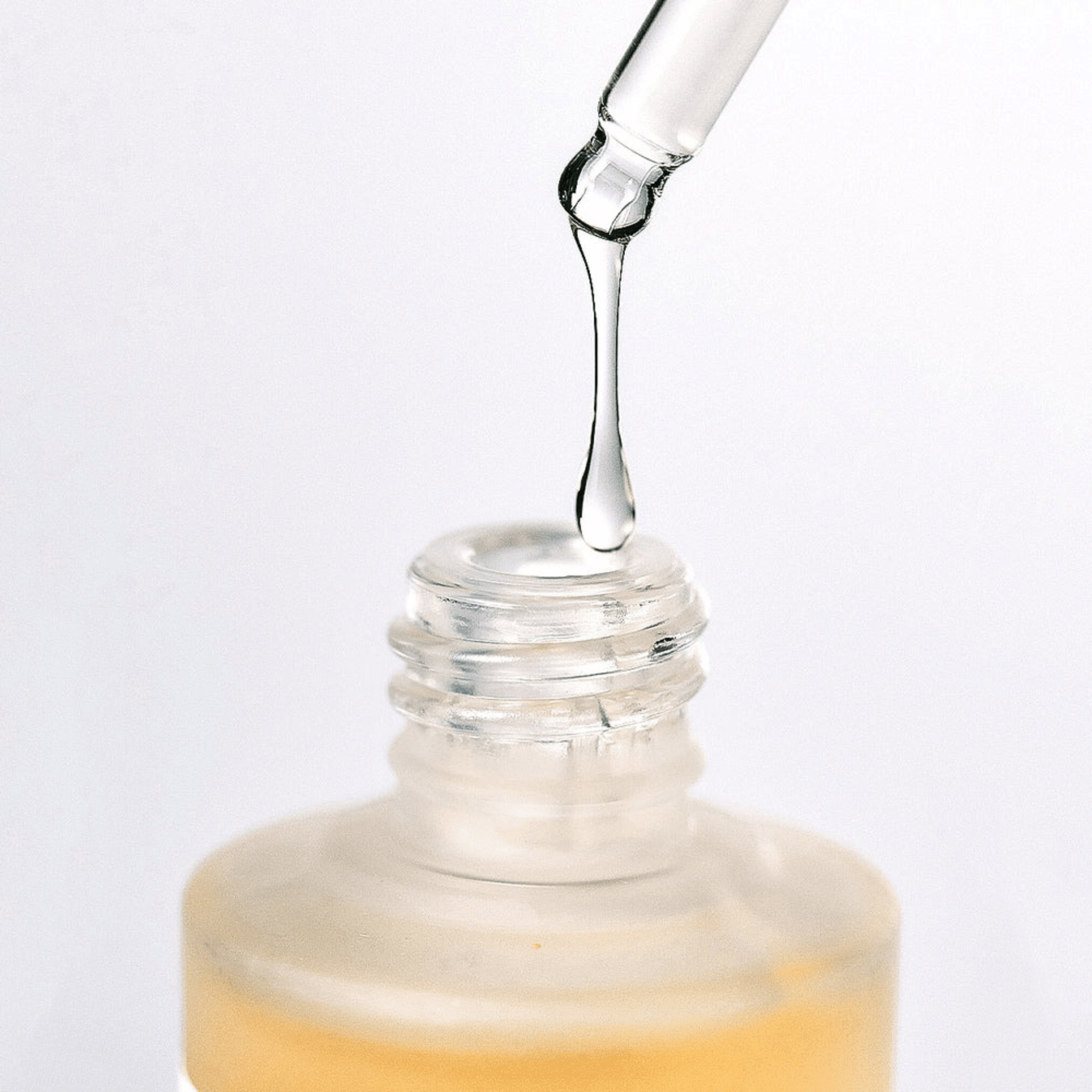 Ein Tropfer spendet klare Flüssigkeit in die Anua Heartleaf 80% Beruhigungsampulle 30ml, die eine gefrostete untere Flaschenhälfte vor einem schlichten weißen Hintergrund aufweist.