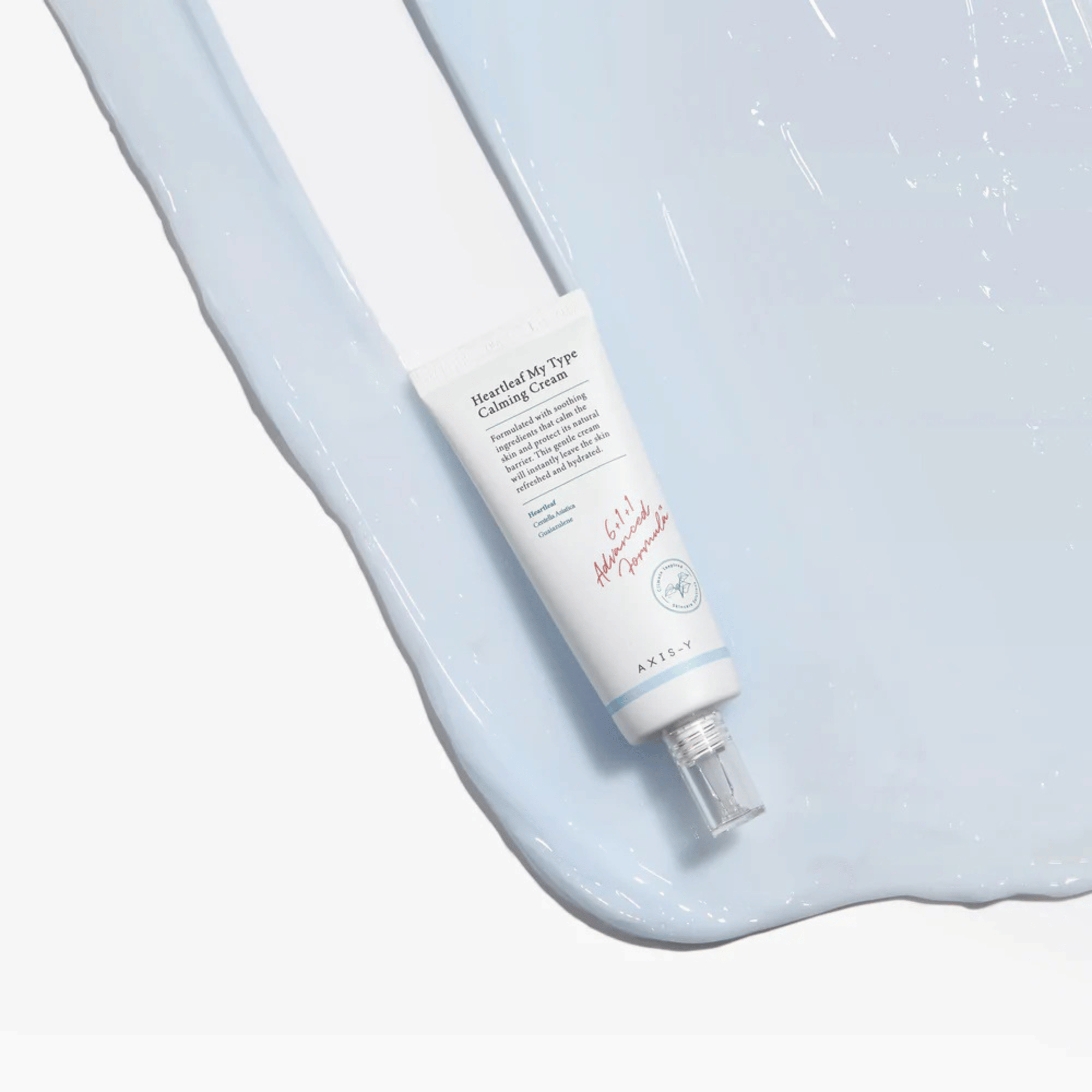 Tube der Axis-Y Heartleaf My Type Calming Cream liegt auf aufgetragener hellblauer Creme vor weißem Hintergrund