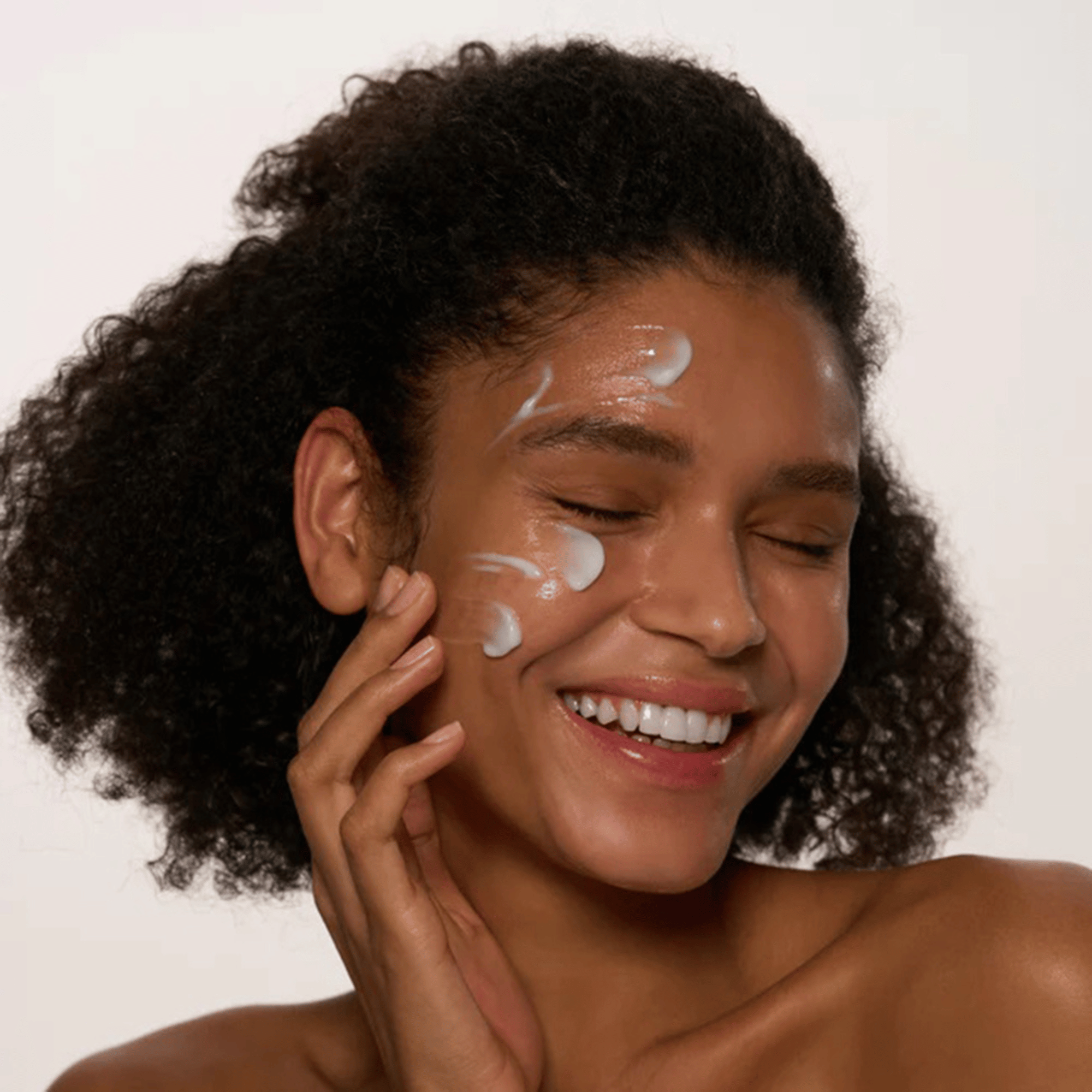 Frau trägt lächelnd mehrere Punkte der Axis-Y Heartleaf My Type Calming Cream auf ihre Wange auf