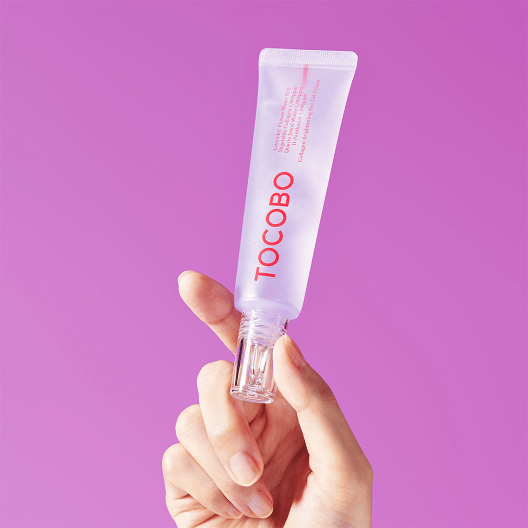 Tocobo Eye Gel Cream in transparenter Tube mit Lavendelfarbton, wird von einer Hand vor violettem Hintergrund gehalten