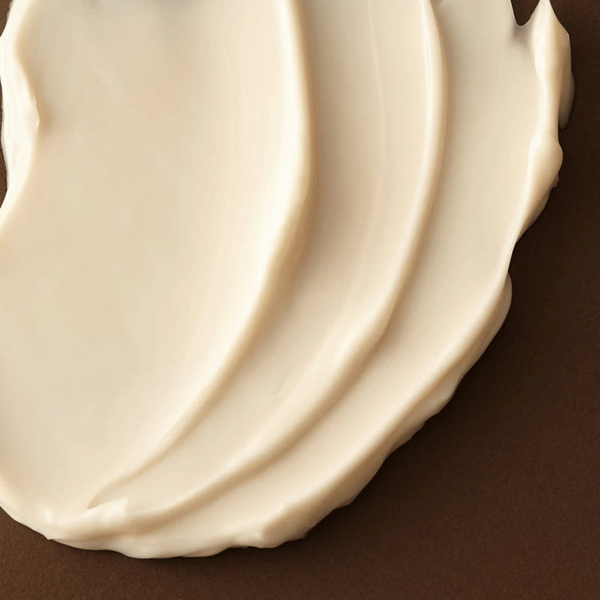 Detailansicht der geschmeidigen Textur der Axis-Y Biome Ultimate Indulging Cream auf braunem Untergrund