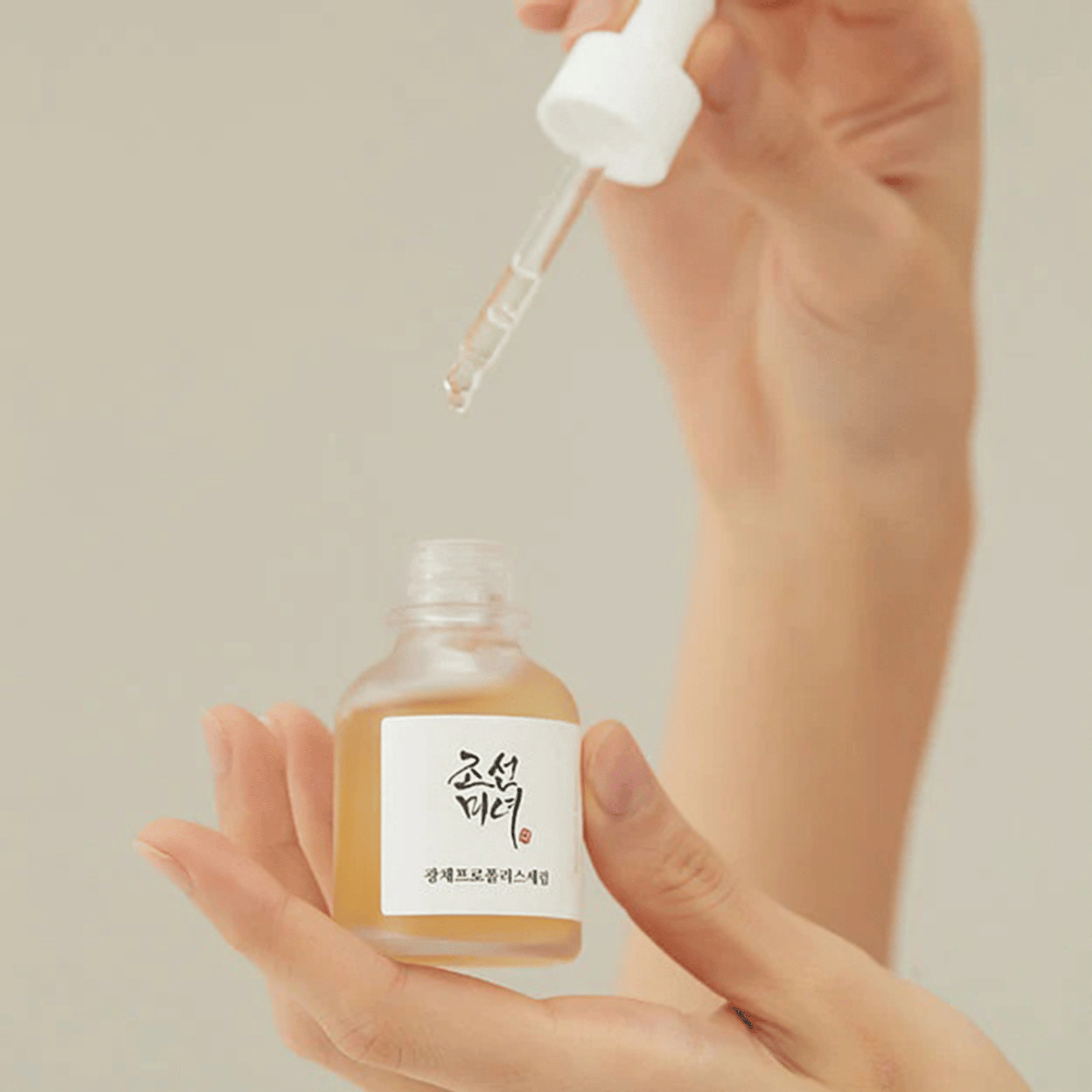 Hand hält Beauty of Joseon Glow Serum während die Textur mit Pipette entnommen wird