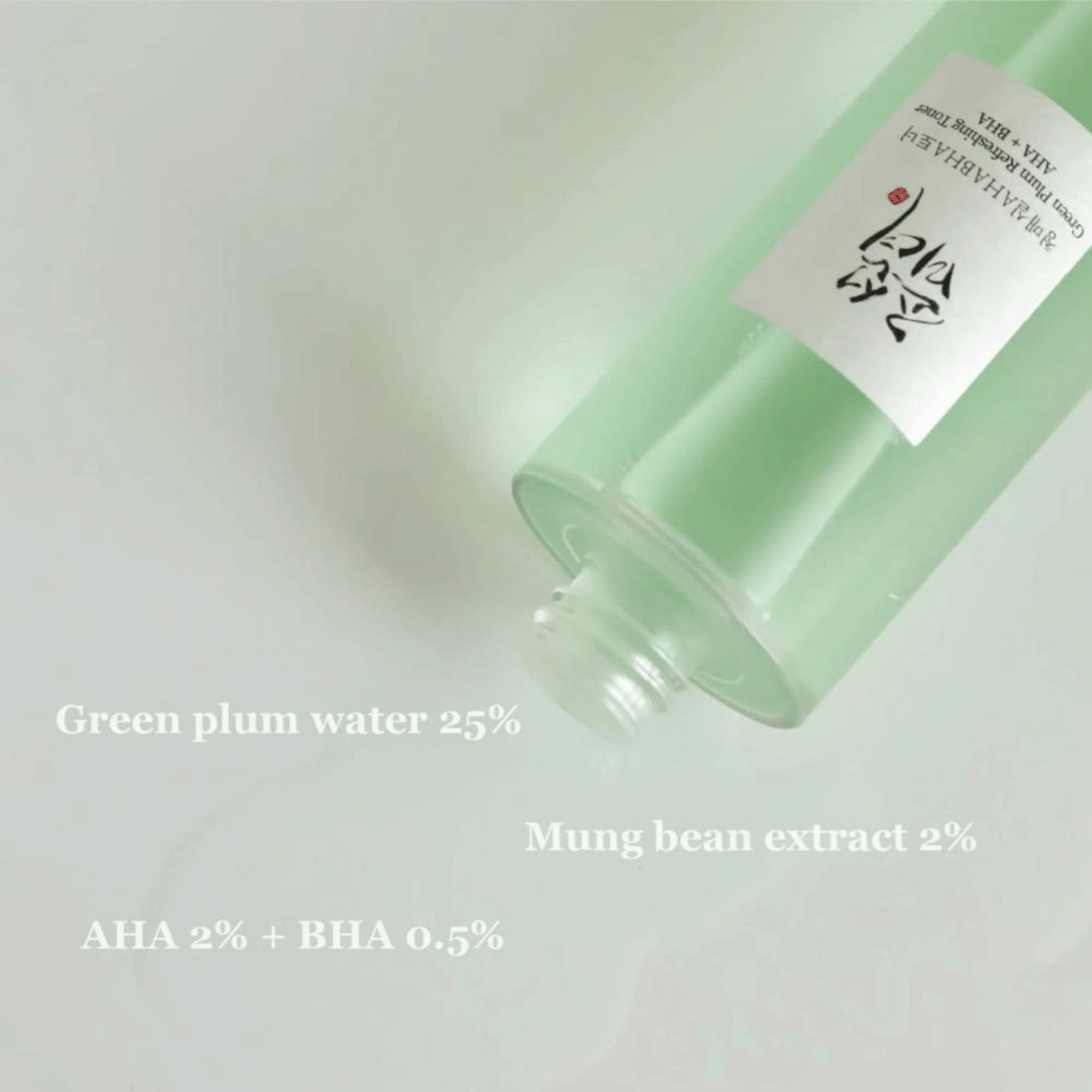 Grünlicher Toner mit 25 % Green Plum Water und AHA + BHA auf einer glatten Oberfläche verteilt