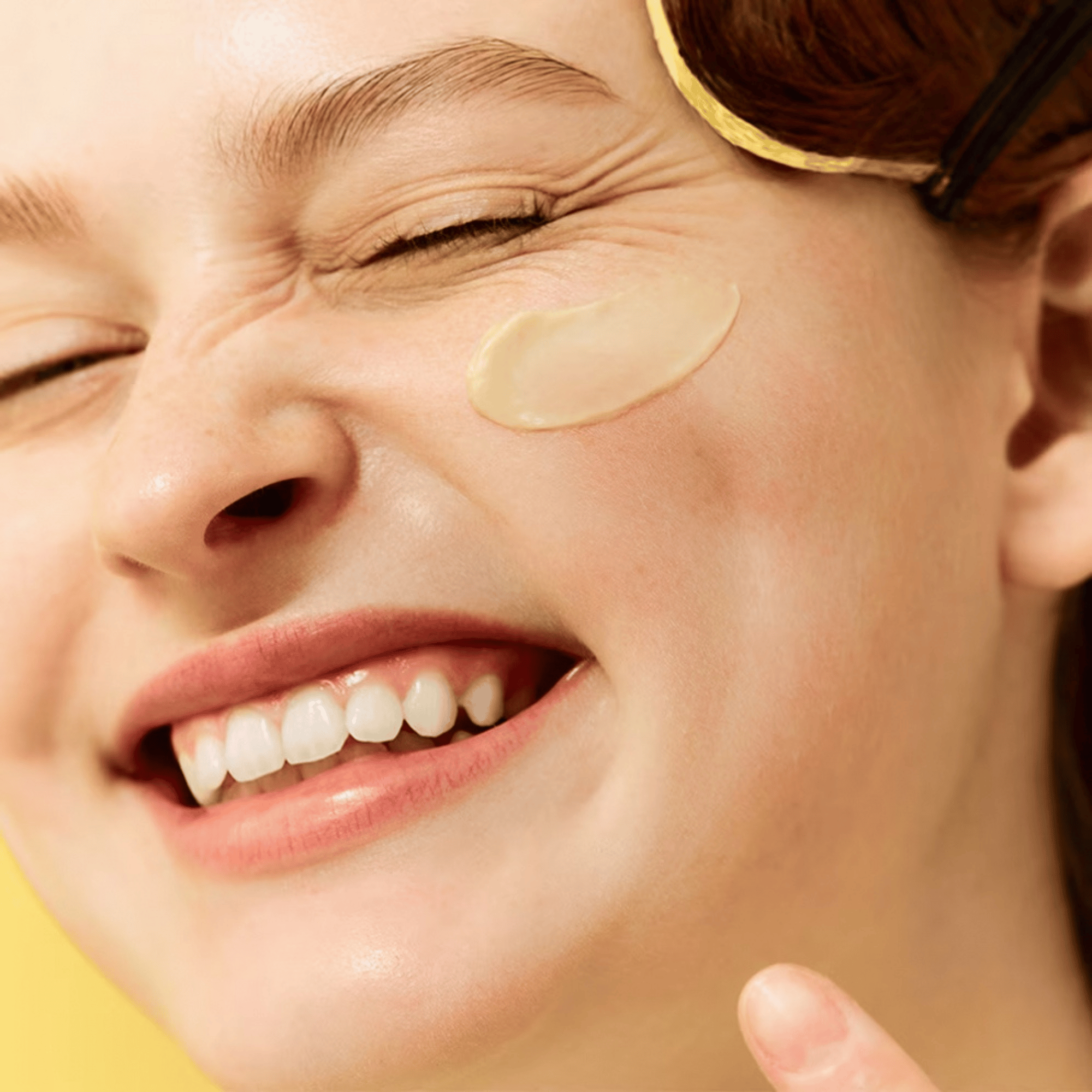 Eine Person lächelt mit geschlossenen Augen und trägt mit dem Finger Dr. Jart+ Ceramidin Skin Barrier Moisturizing Cream auf ihre Wange auf.