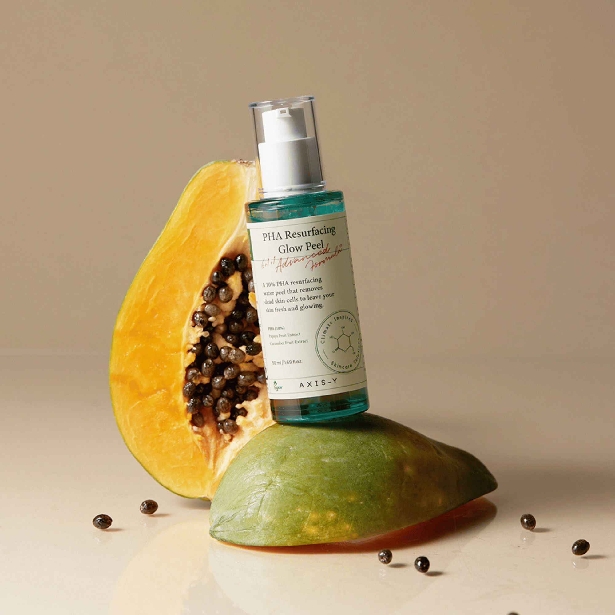 Axis-Y PHA Resurfacing Glow Peel steht auf halber Papaya mit aufgestellter Flasche, frische Kerne rundherum verstreut