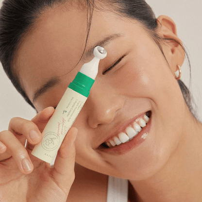 Frau trägt AXIS-Y Vegan Collagen Eye Serum lächelnd unter dem Auge auf, Nahaufnahme mit Applikator