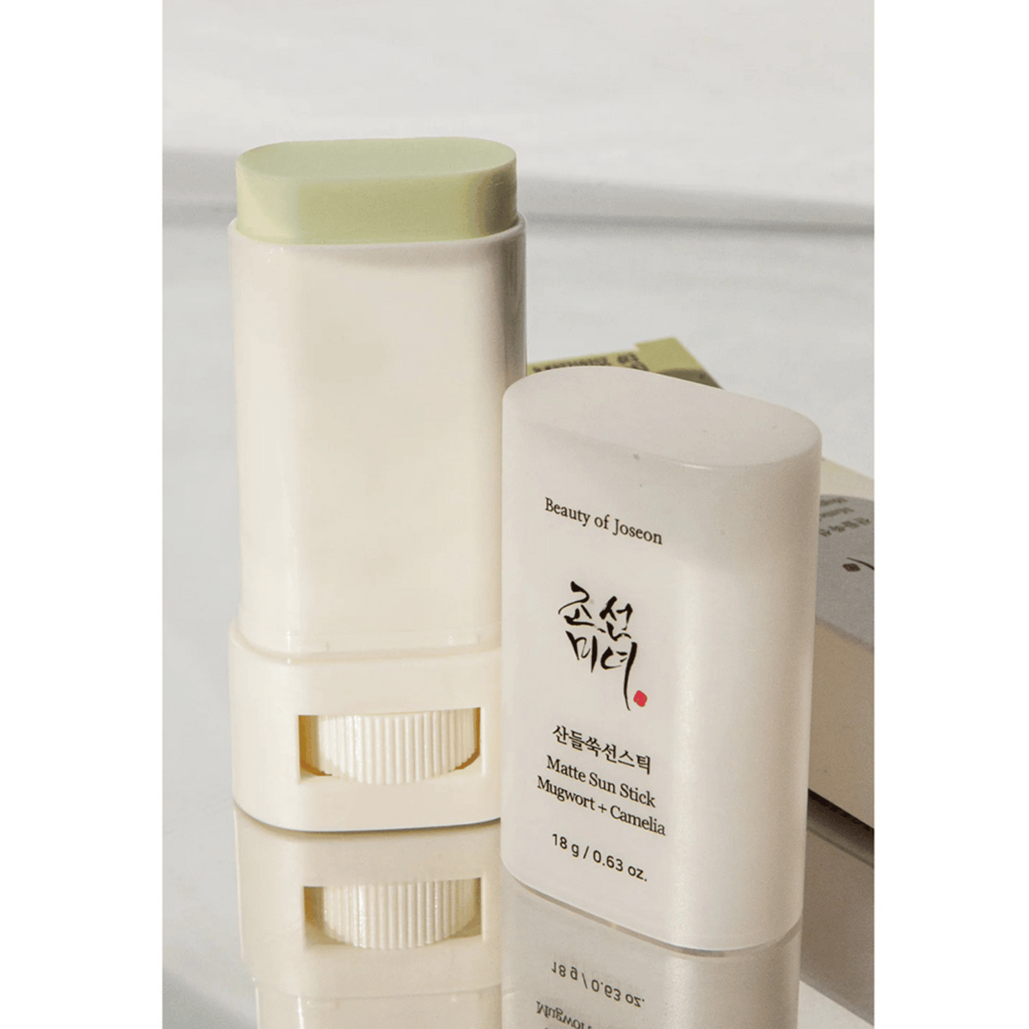 Beauty of Joseon Matte Sun Stick Mugwort &amp; Camelia mit geöffneter Kappe, freigestellt auf reflektierender Fläche