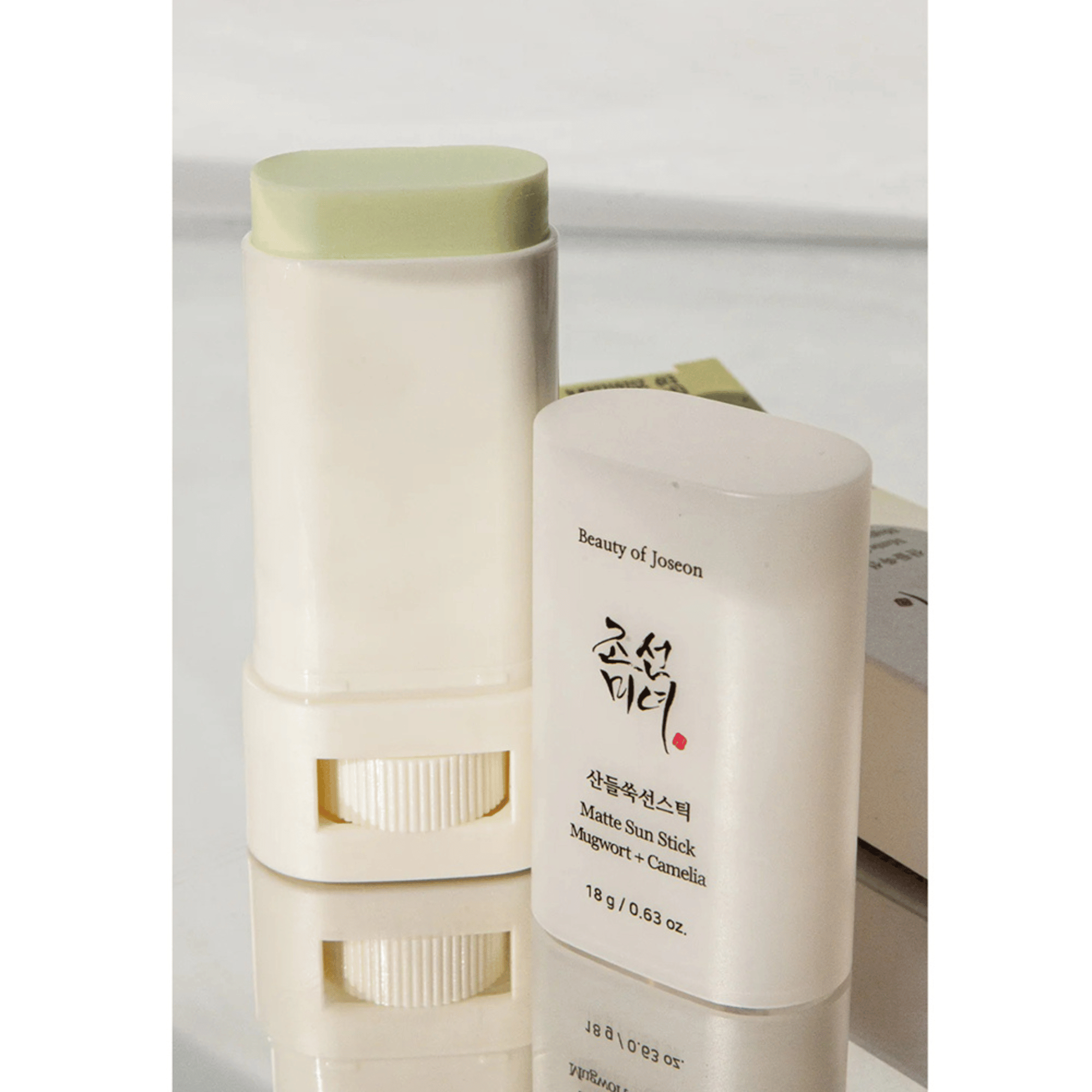 Beauty of Joseon Matte Sun Stick Mugwort &amp; Camelia mit geöffneter Kappe, freigestellt auf reflektierender Fläche